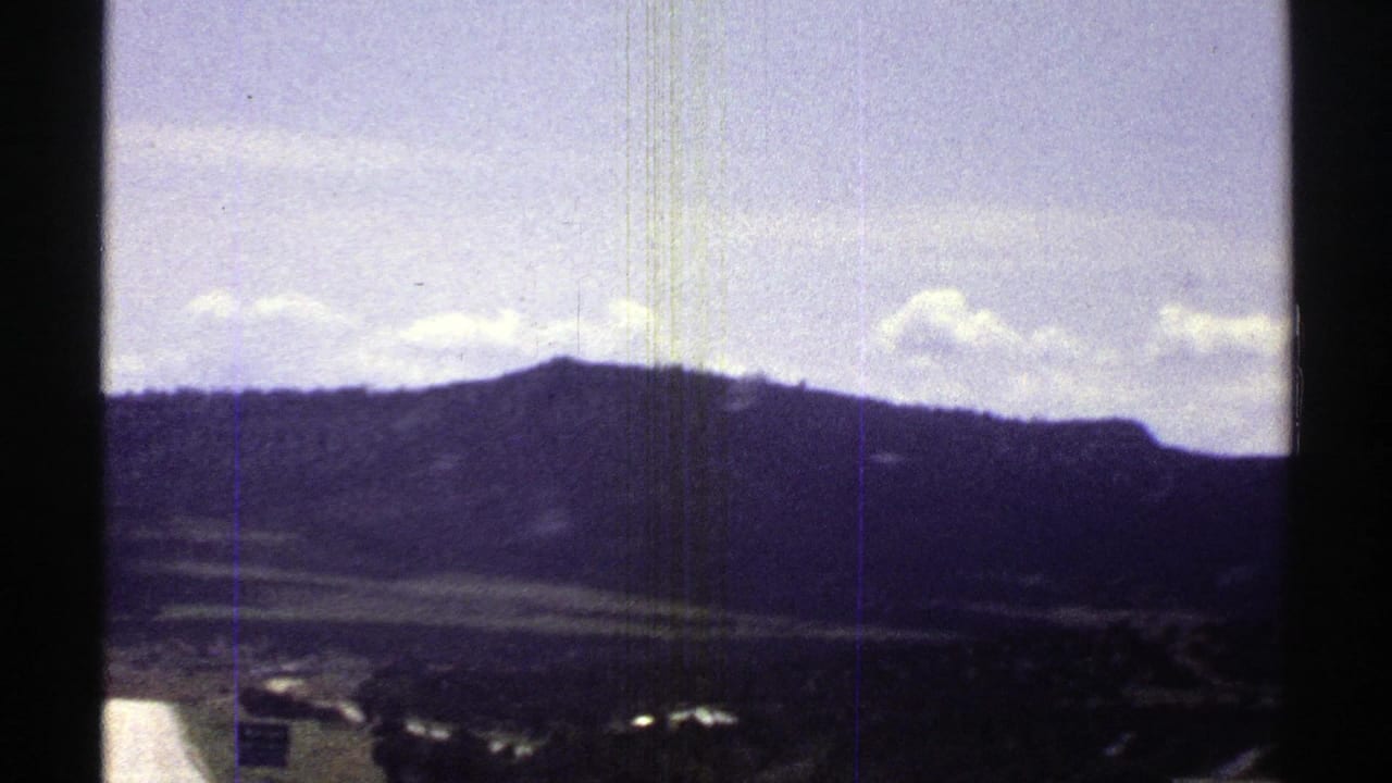 Mountain ridge and pale sky seen through a moving car window with film frame borders.