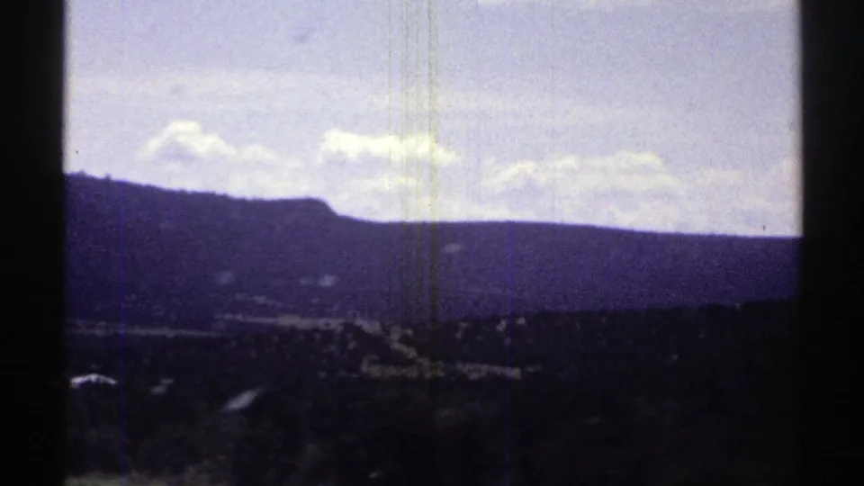 1969 Arizona 8mm frame looking across a valley toward low mountains beneath a bright, lightly clouded sky.