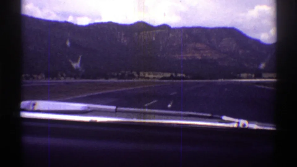 1969 Arizona 8mm driving view with the car dashboard at bottom, road ahead, and mountains beyond the windshield.