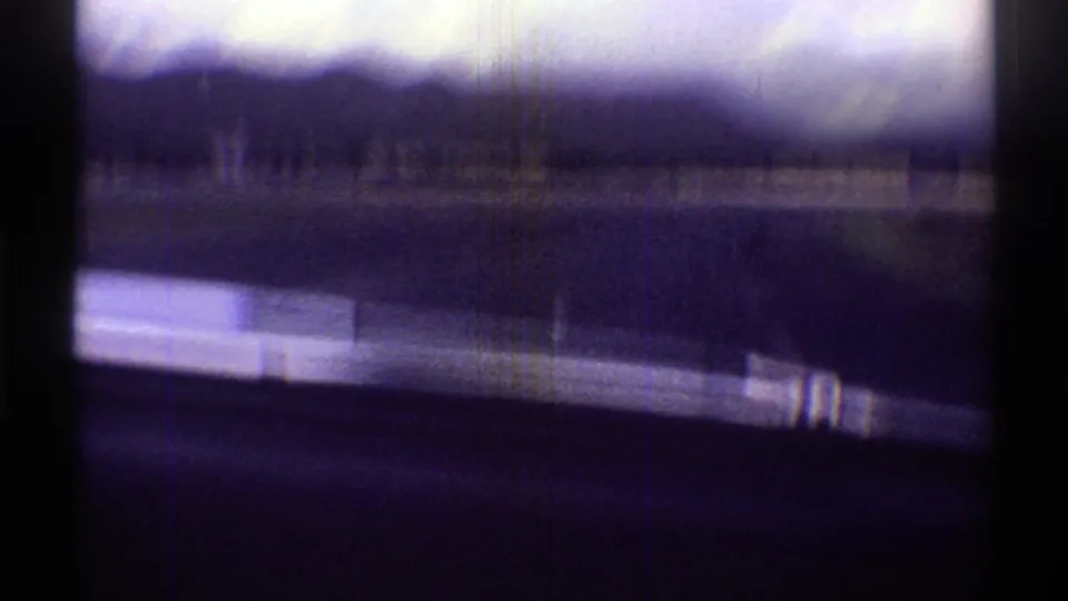 Motion-blurred 1969 Arizona driving view, with the windshield edge, road surface, and mountains partly visible.