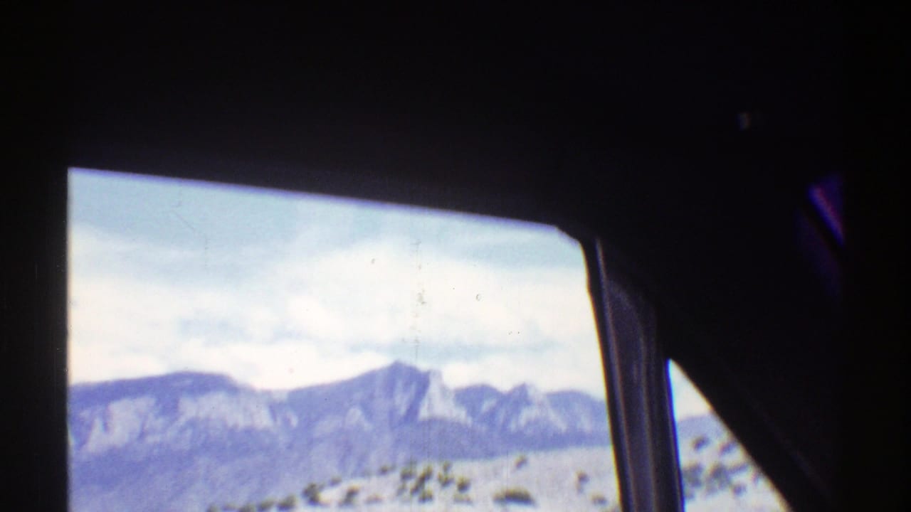 Mountain range and pale sky framed by the interior of a vehicle.