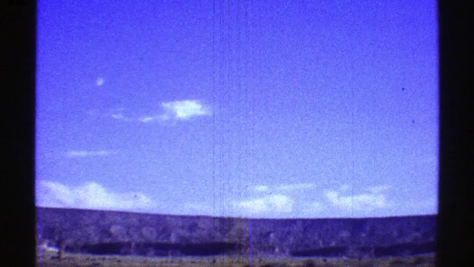Arizona 8mm travel frame showing white clouds, a deep blue sky, distant desert terrain, and motion-softened foreground.