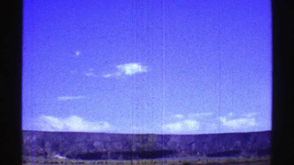 1969 Arizona road-trip view of open sky and desert horizon, rendered with blue color shift, grain, and vertical film marks.