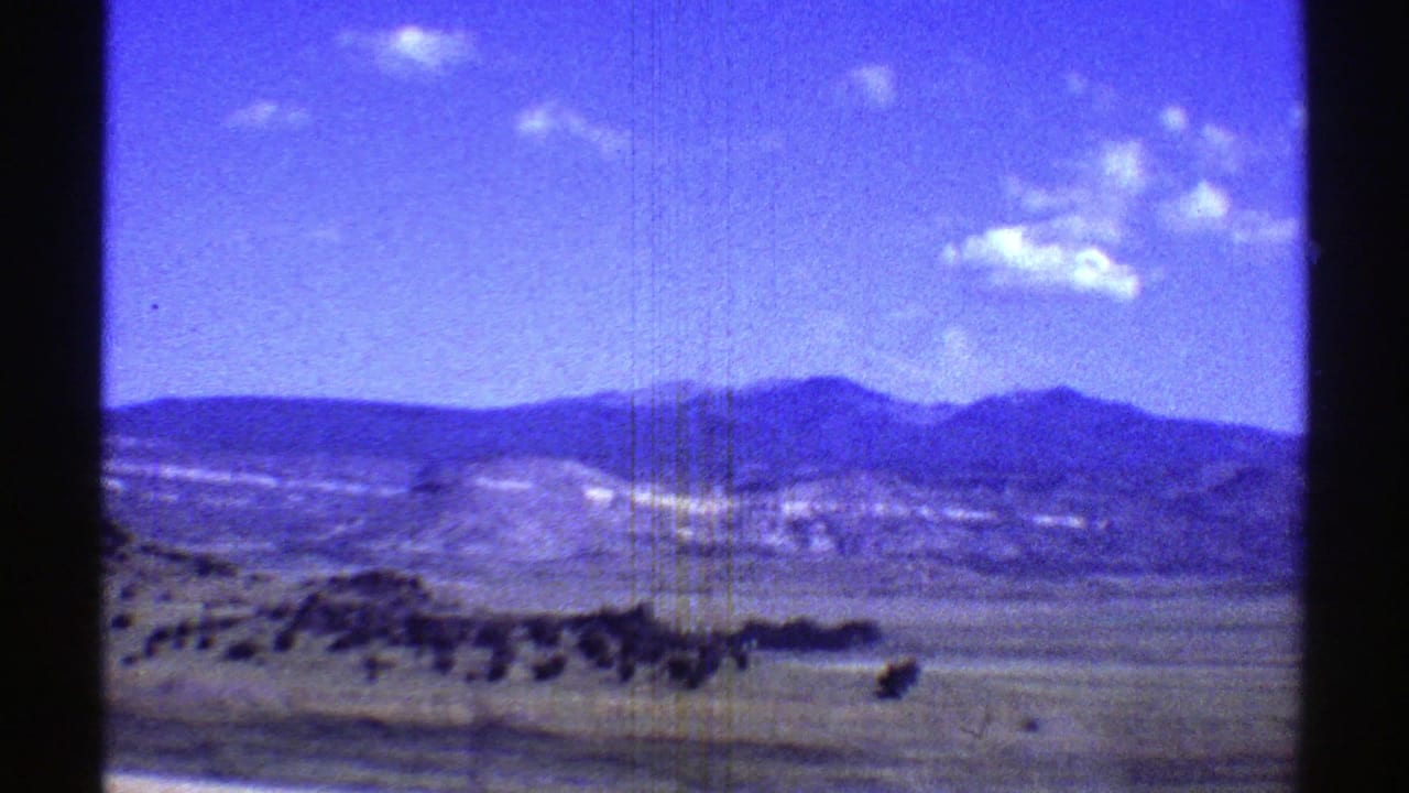 Open desert valley with distant mountains and small clouds behind a contact-sheet divider.