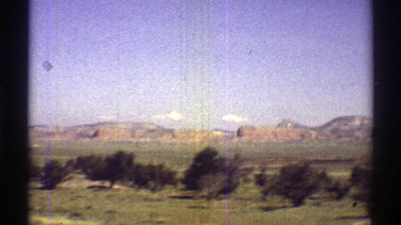 1969 Arizona home-movie view of green desert vegetation, low hills, and a bright sky seen through an 8mm frame.