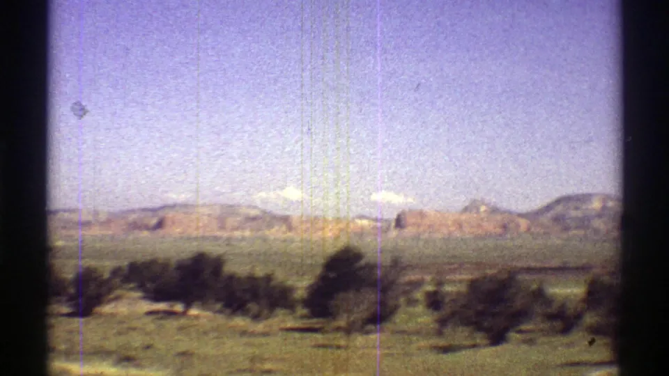 1969 Arizona home-movie view of green desert vegetation, low hills, and a bright sky seen through an 8mm frame.