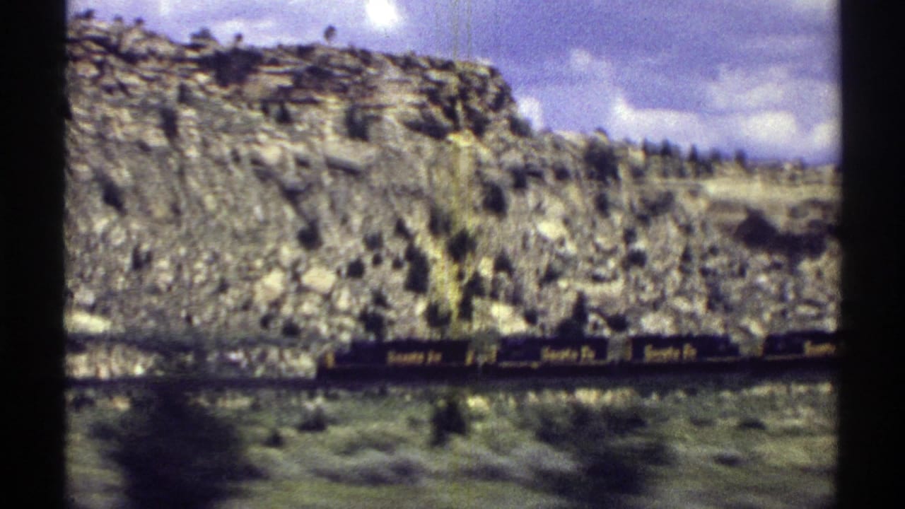 Santa Fe freight train passing below rocky desert hills.