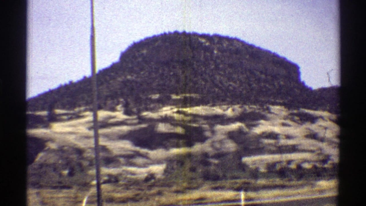 Rounded rocky hill seen from a moving train window.