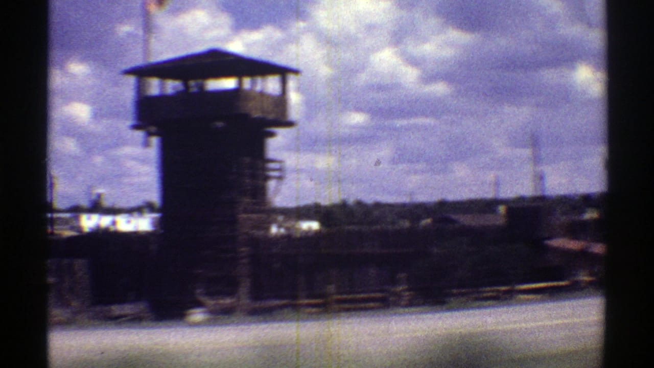 1969 Arizona home-movie view of a prison guard tower, fencing, and low buildings filmed from a passing vehicle.