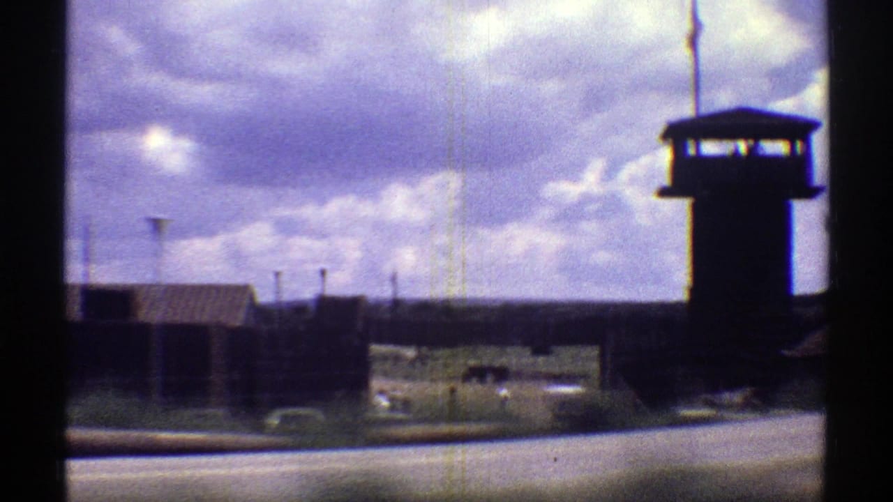 A roadside view of a prison tower, perimeter fencing, and institutional buildings in Arizona, captured on 8mm film in 1969.