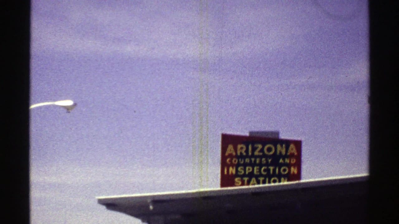 1969 Arizona road-trip frame showing a Courtesy and Inspection Station sign partly framed by 8mm film borders.
