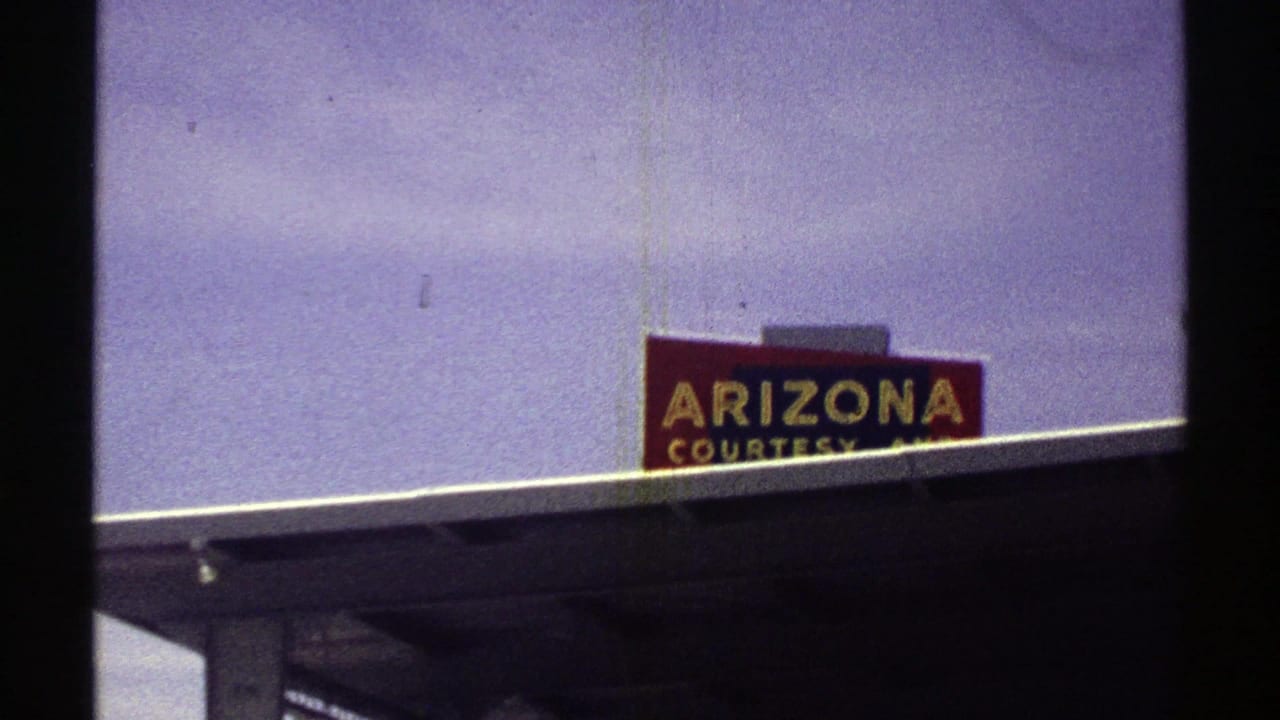 1969 Arizona home-movie view of a cropped Arizona Courtesy sign over a roadside station canopy.