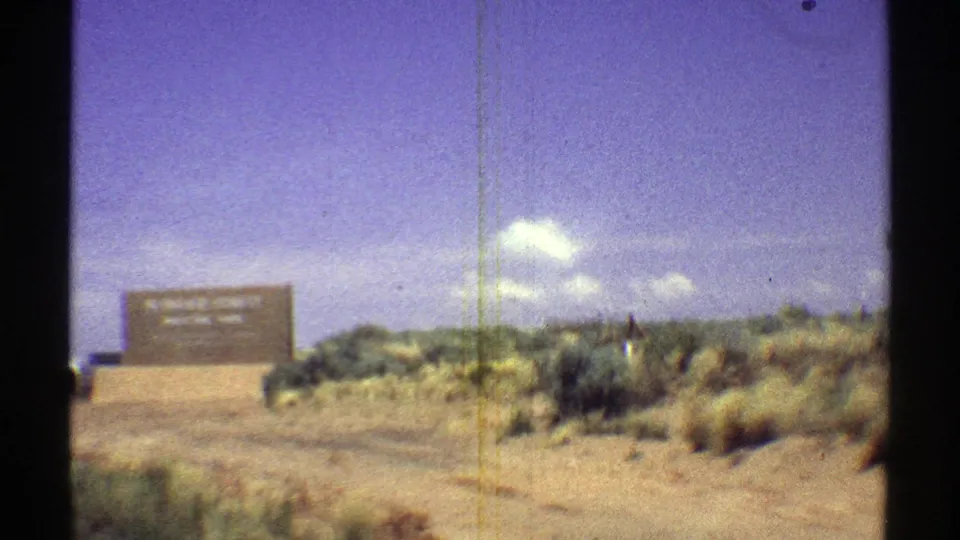 1969 Arizona frame with the Petrified Forest National Park entrance sign in a desert roadside landscape.