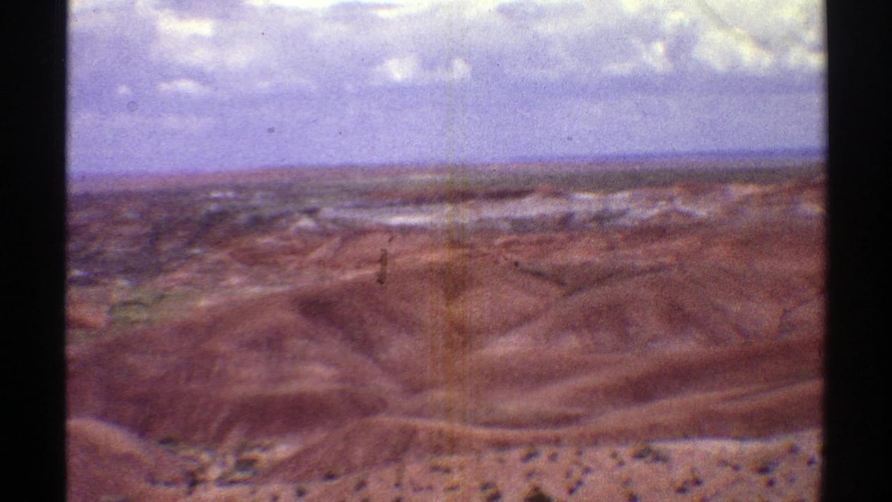 Reddish-brown desert hills beneath a blue sky with puffy white clouds.