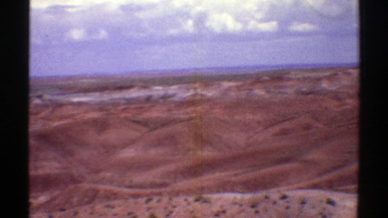 Brown desert hills beneath a blue sky with scattered white clouds.
