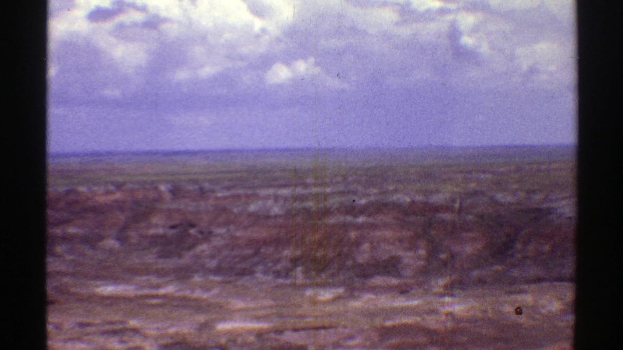 Open dry landscape and distant horizon beneath a cloudy sky.
