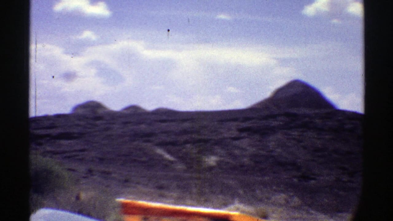 Rocky desert hills seen through dark car-window framing.