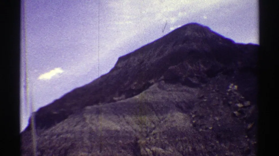 1969 Arizona 8mm frame of a rocky peak and dry hillside, with scratches and grain visible across the scan.