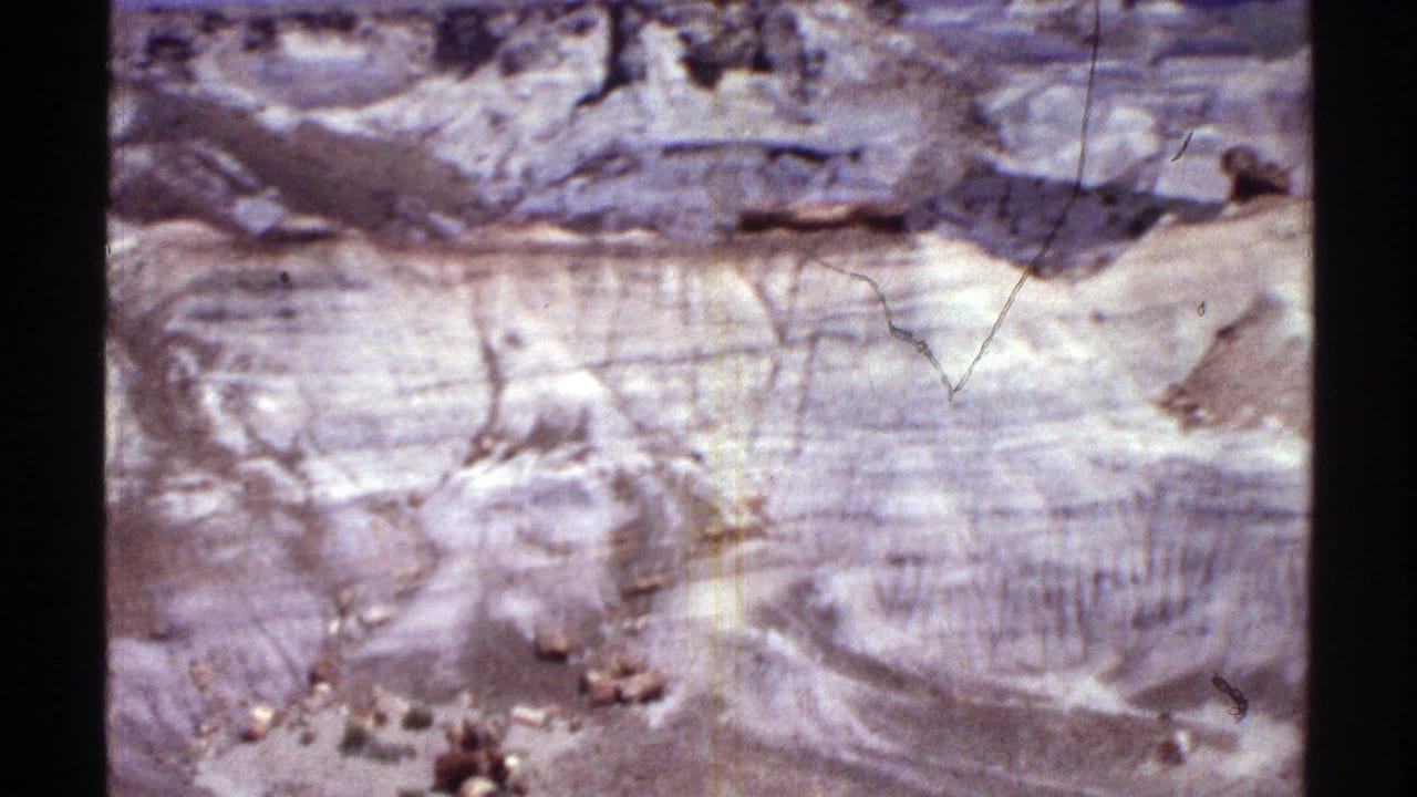Pale eroded rock face and layered desert formations seen from above.