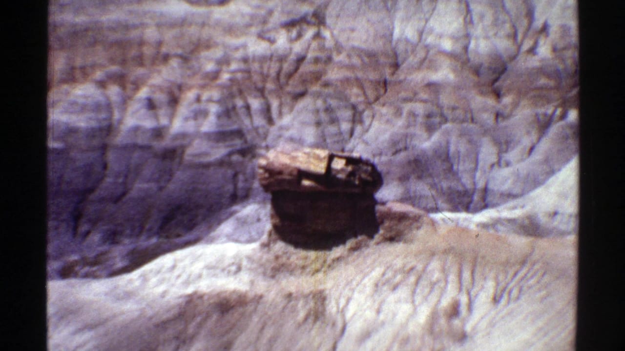 1969 Arizona 8mm frame showing an unusual cylindrical rock formation set against striated canyon terrain.
