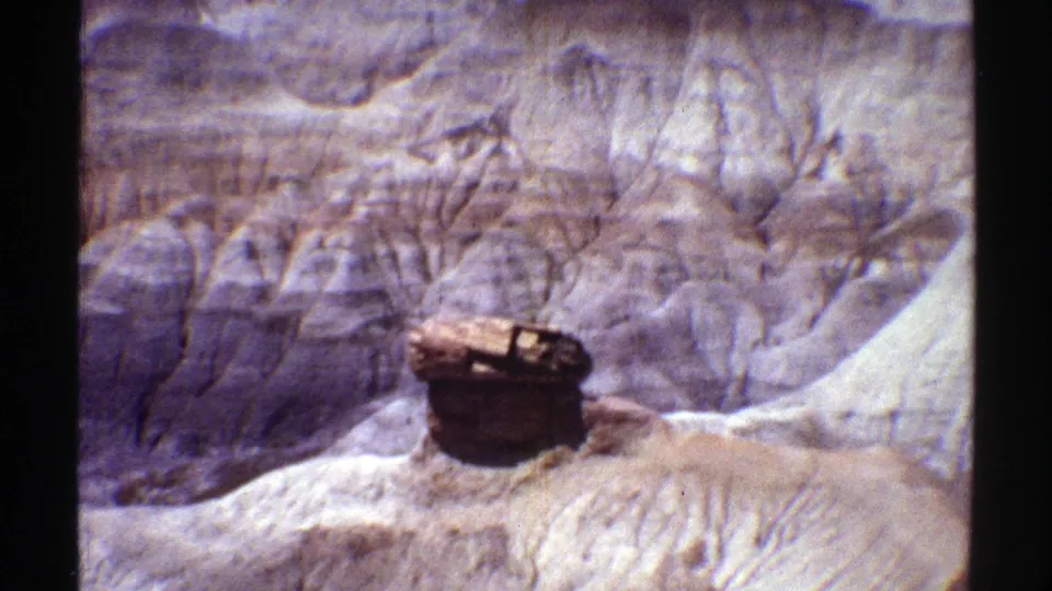 Vintage 8mm Arizona canyon frame showing the rock formation slightly lower in the composition amid eroded strata.