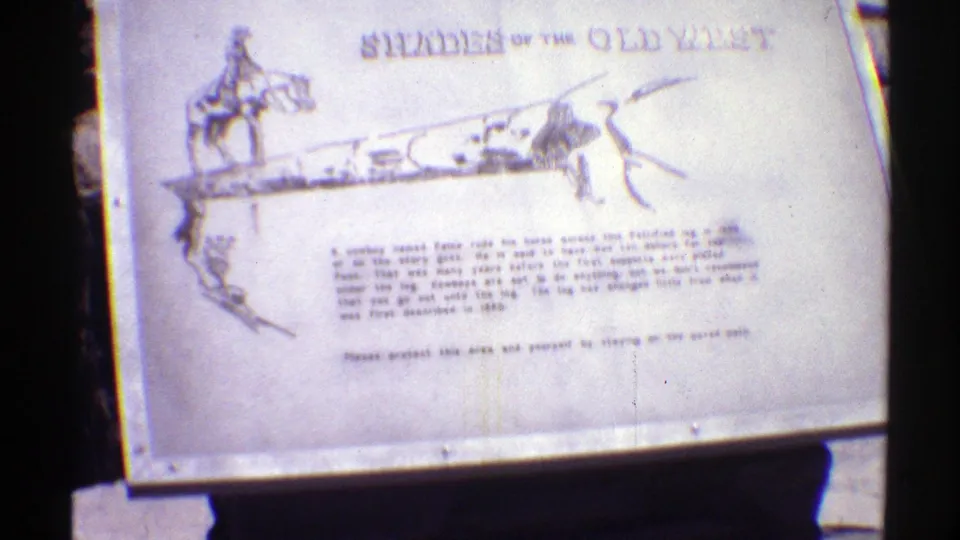 1969 Arizona 8mm frame showing a roadside historical sign titled "Shades of the Old West" with cowboy artwork and printed text.
