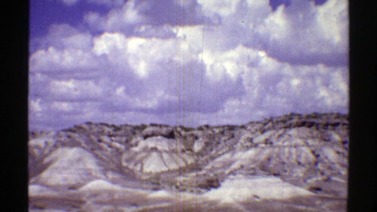 Arizona desert badlands under a cloud-filled sky in 1969 home-movie road-trip footage.