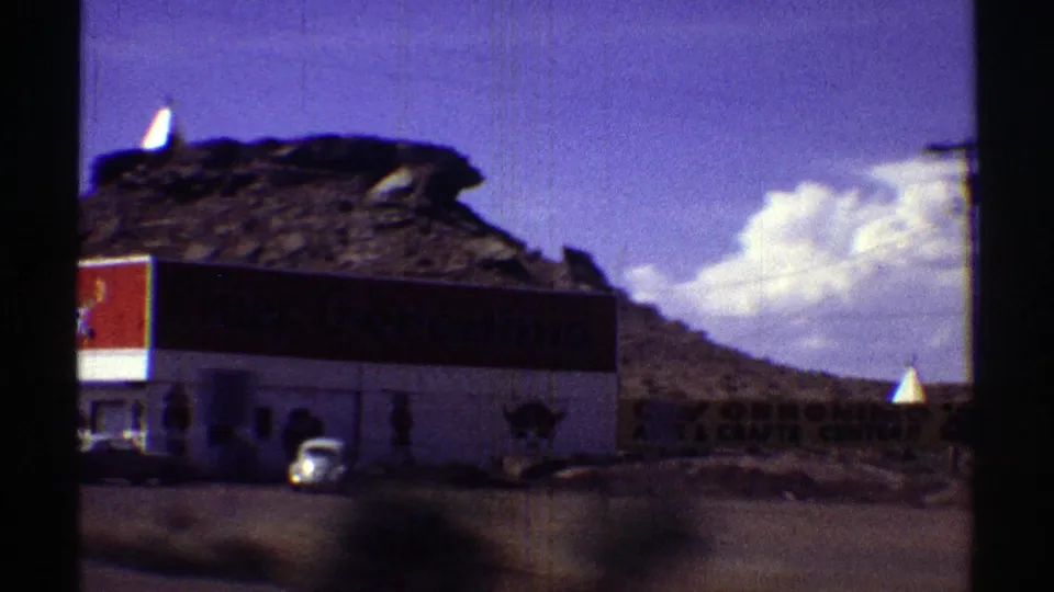 A roadside stop in Arizona appears beside rocky desert terrain, with a red sign and parked car visible.