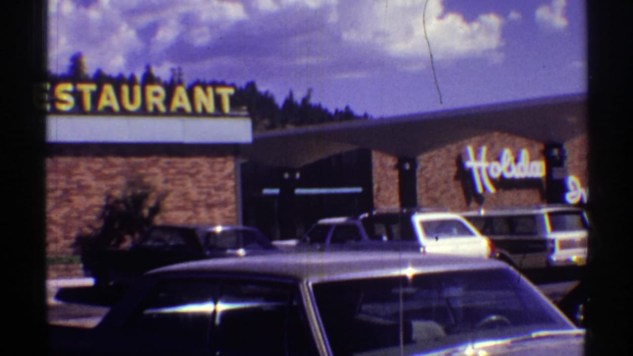 Restaurant sign and Holiday Inn frontage with several parked cars in the foreground.