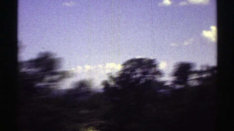 Moving 8mm frame from Arizona showing blurred roadside vegetation against a bright sky and open terrain.