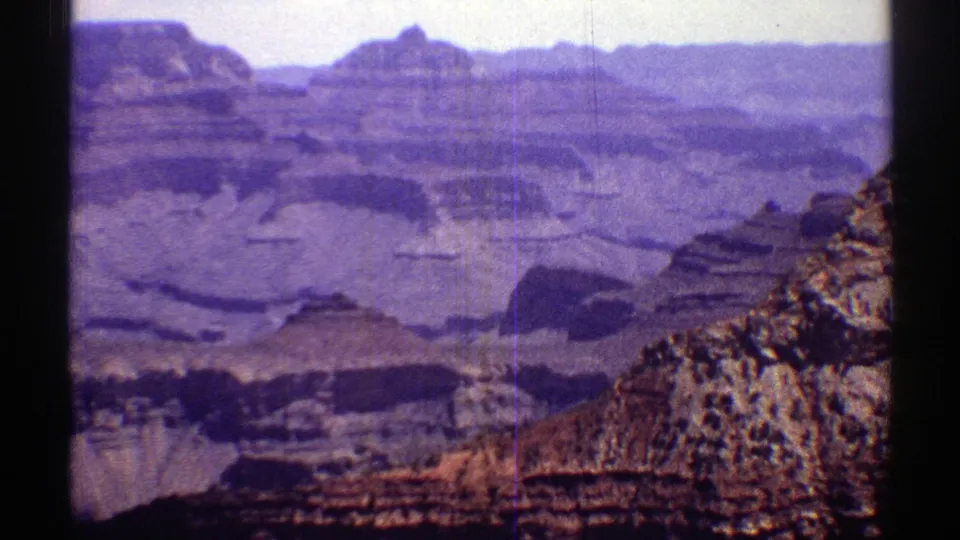 Vintage 1969 Arizona travel frame with a canyon panorama, stratified cliffs, distant buttes, and rocky foreground texture.