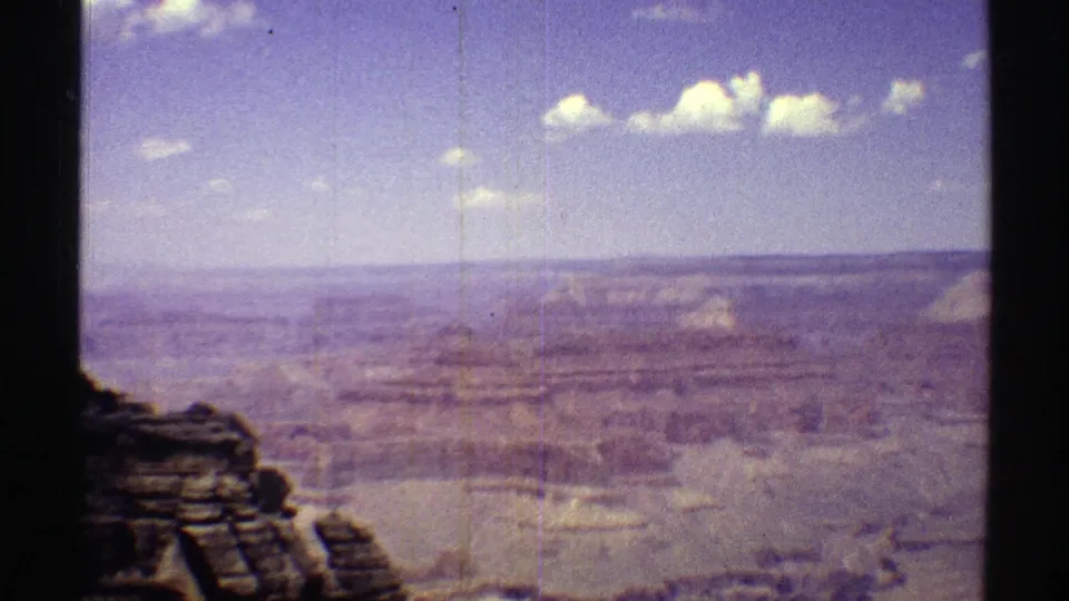 Wide Grand Canyon landscape in 1969 Arizona footage, showing layered rock, distant mesas, haze, and visible 8mm film texture.