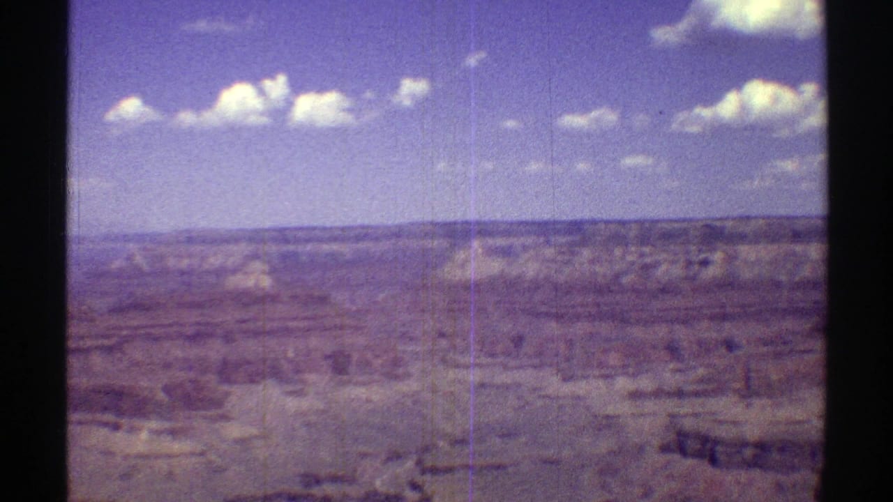 1969 8mm home-movie frame showing a wide Grand Canyon vista in Arizona beneath scattered white clouds.
