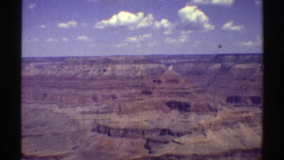 1969 8mm frame of the Grand Canyon landscape, with soft focus, faded color, and visible rock ledges.