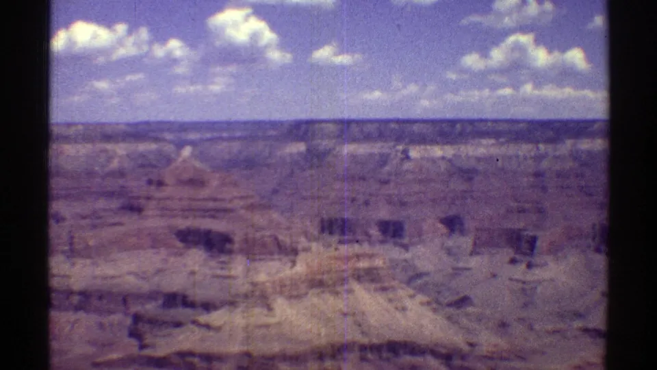 Late-1960s Arizona home-movie frame showing a broad Grand Canyon overlook view with layered cliffs and clouds.