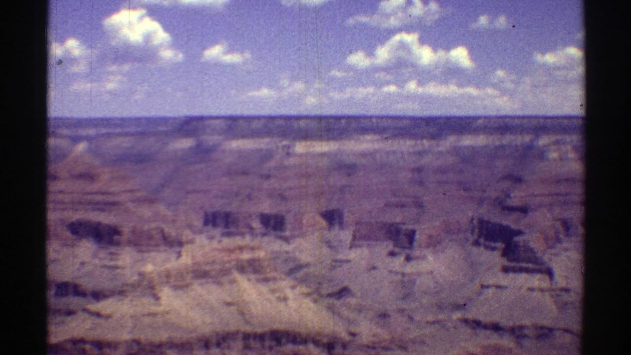 Wide canyon landscape beneath a blue sky with film-frame borders visible.