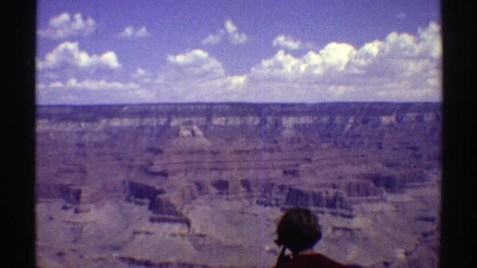 1969 8mm Arizona canyon panorama with a foreground tourist seen from behind near the overlook.