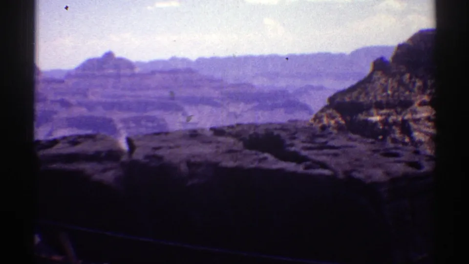 1969 Arizona 8mm frame showing a wide Grand Canyon panorama with foreground rock and hazy layered formations.