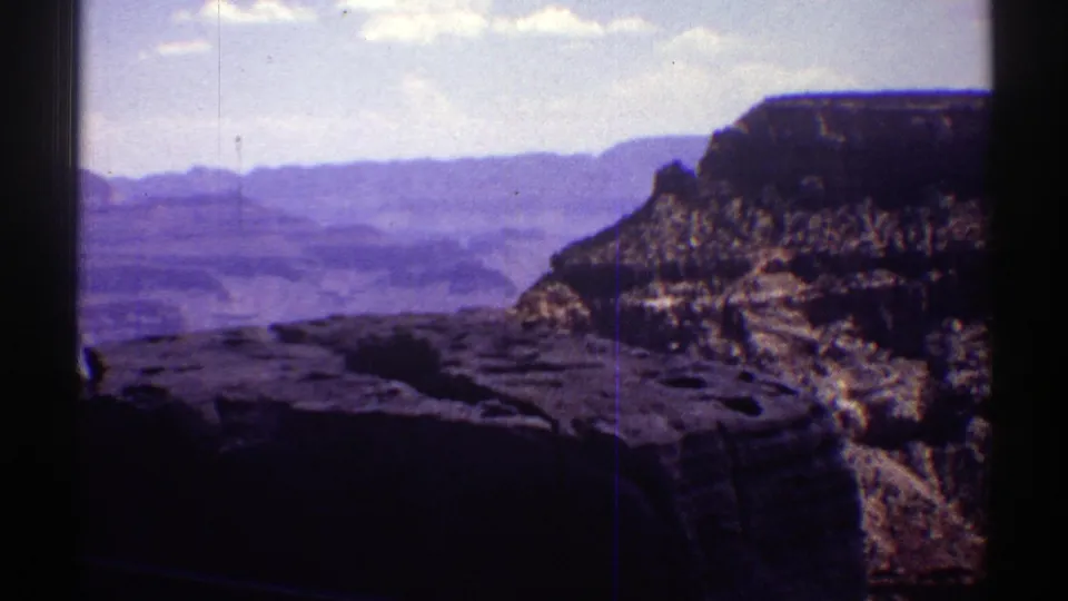 1969 Arizona 8mm frame of Grand Canyon cliffs and a rocky overlook shelf near the end of the slow pan.