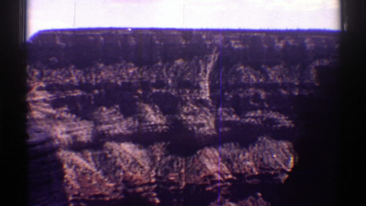 Sunlit canyon cliffs with horizontal rock layers and dark frame edges.