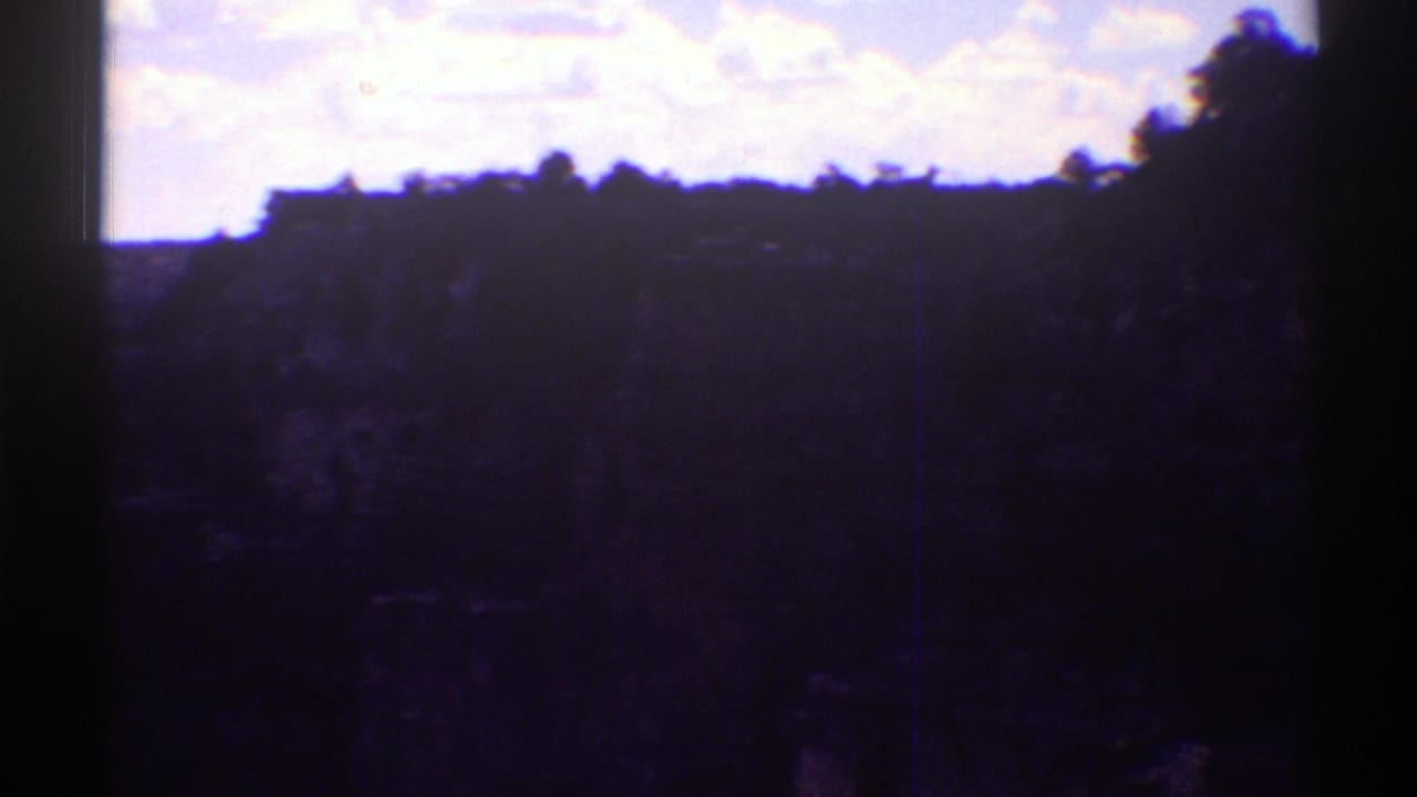 Dark canyon silhouette below a bright sky within a film contact frame.
