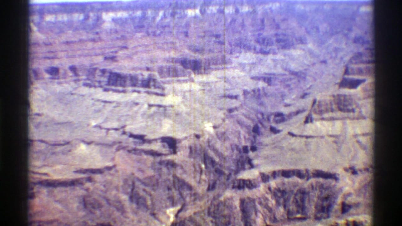 Aerial view across layered desert canyon walls and pale rock shelves.