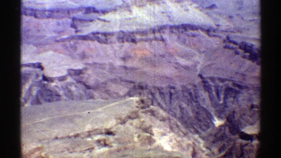 1969 Arizona 8mm frame with a wide view across pale desert foreground and layered ridges under bright sun.