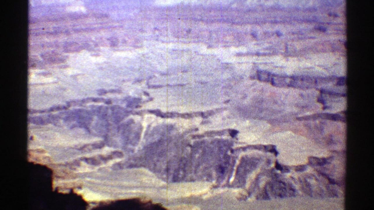 1969 Arizona 8mm panorama across rocky canyon shelves and distant plateau under bright daylight.
