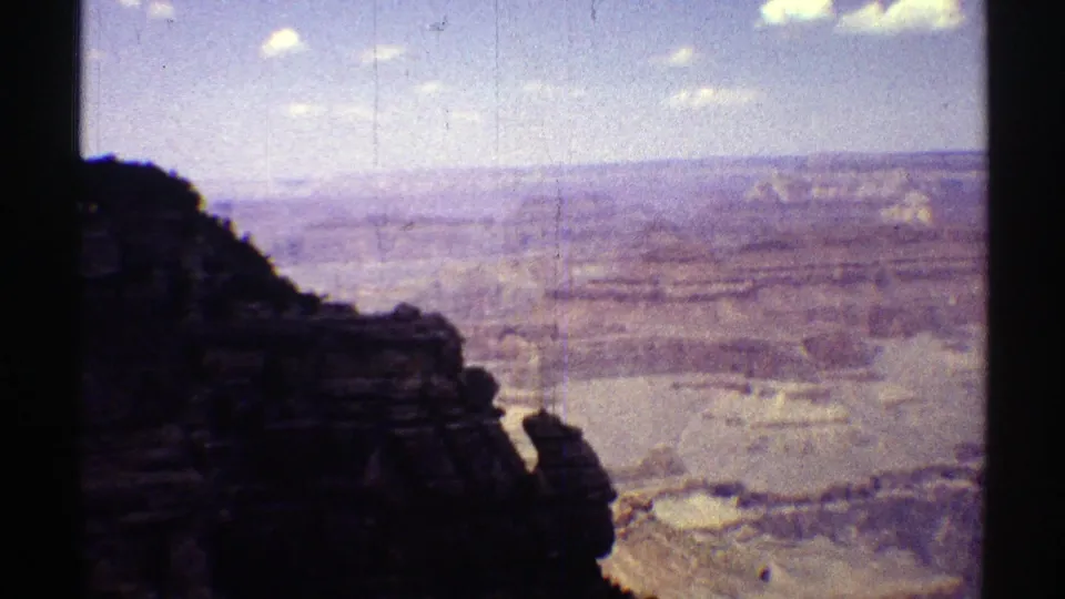 1969 Arizona 8mm shot from a rocky overlook toward layered desert canyon terrain.