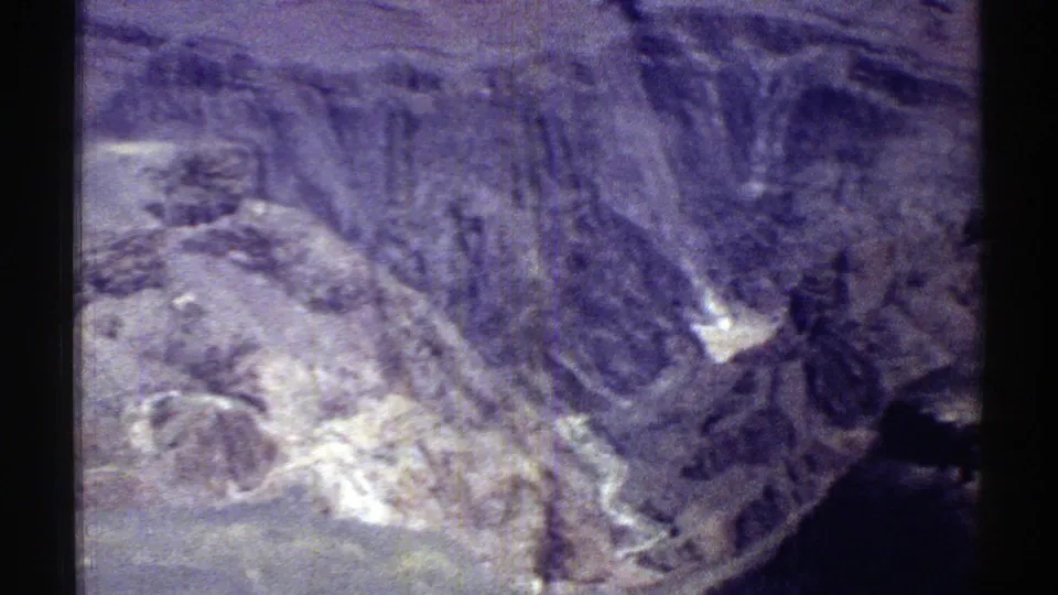 1969 Arizona 8mm frame showing rugged rocky slopes, canyon-like contours, and deep shadows during a landscape pan.