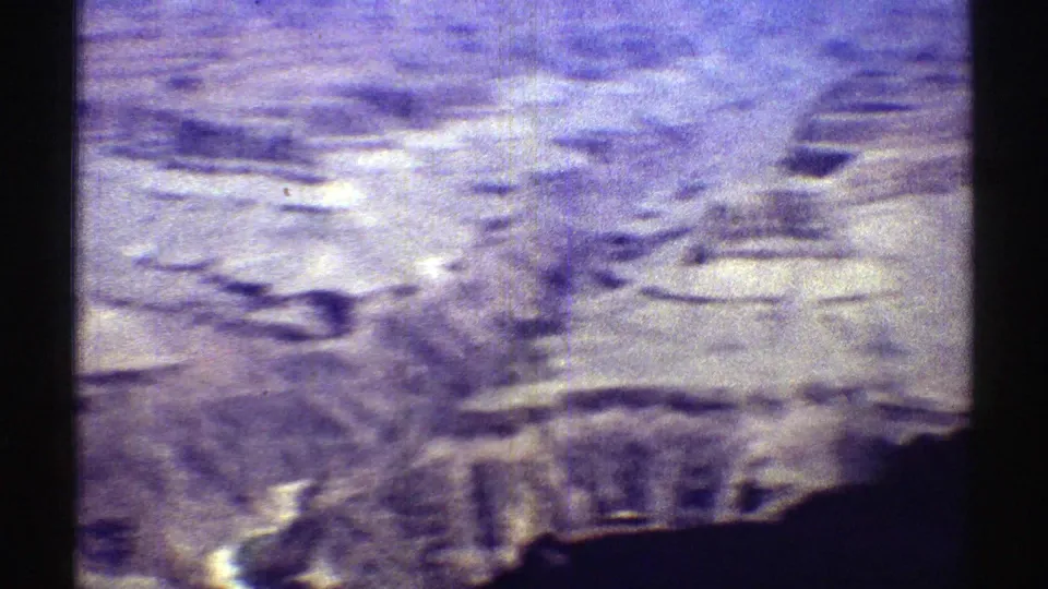 1969 8mm Arizona aerial view of rugged mesa and canyon formations with grain, scratches, and faded color.