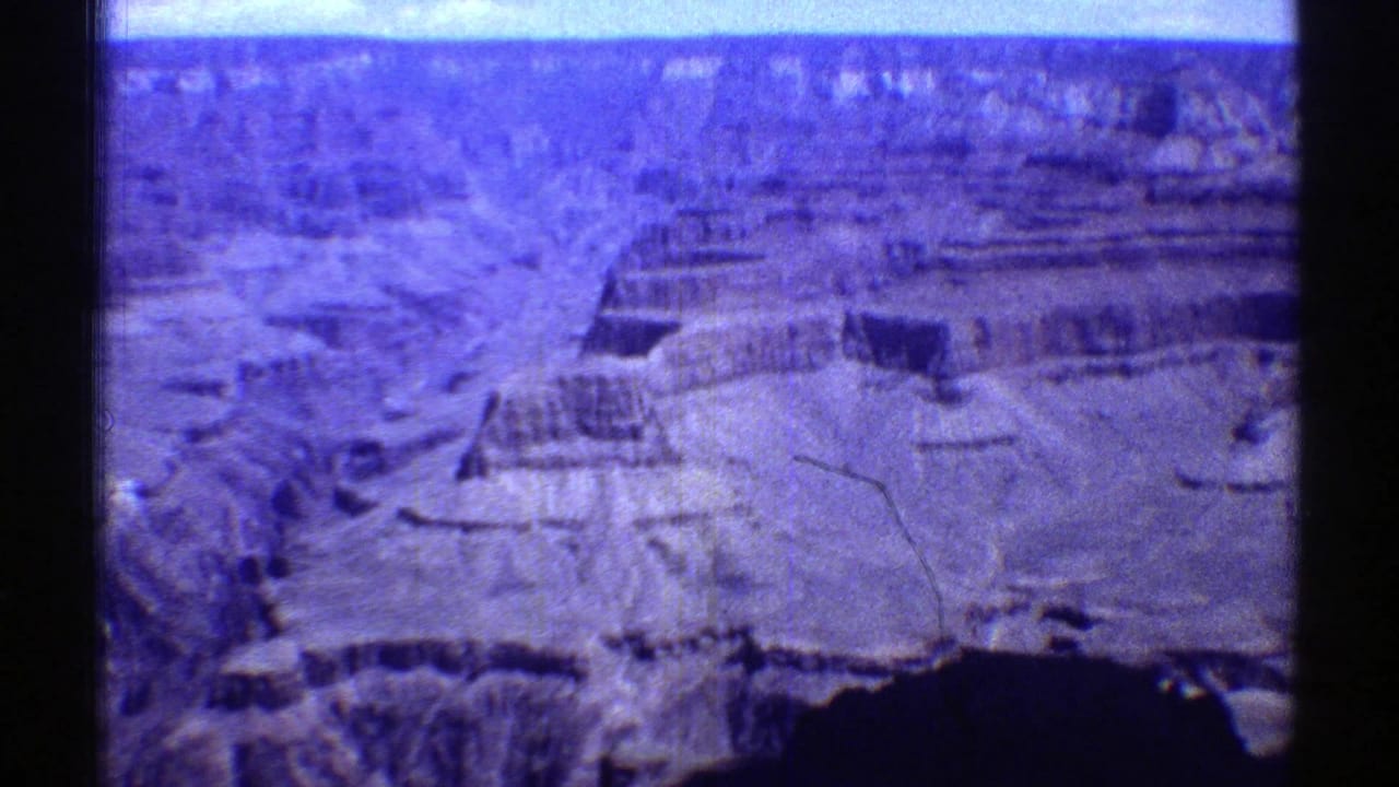 1969 8mm home-movie frame showing a high Arizona view across the Grand Canyon, with layered cliffs and visible film gate edges.