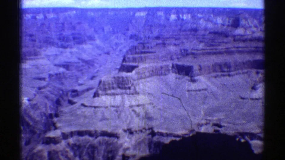 1969 8mm home-movie frame showing a high Arizona view across the Grand Canyon, with layered cliffs and visible film gate edges.