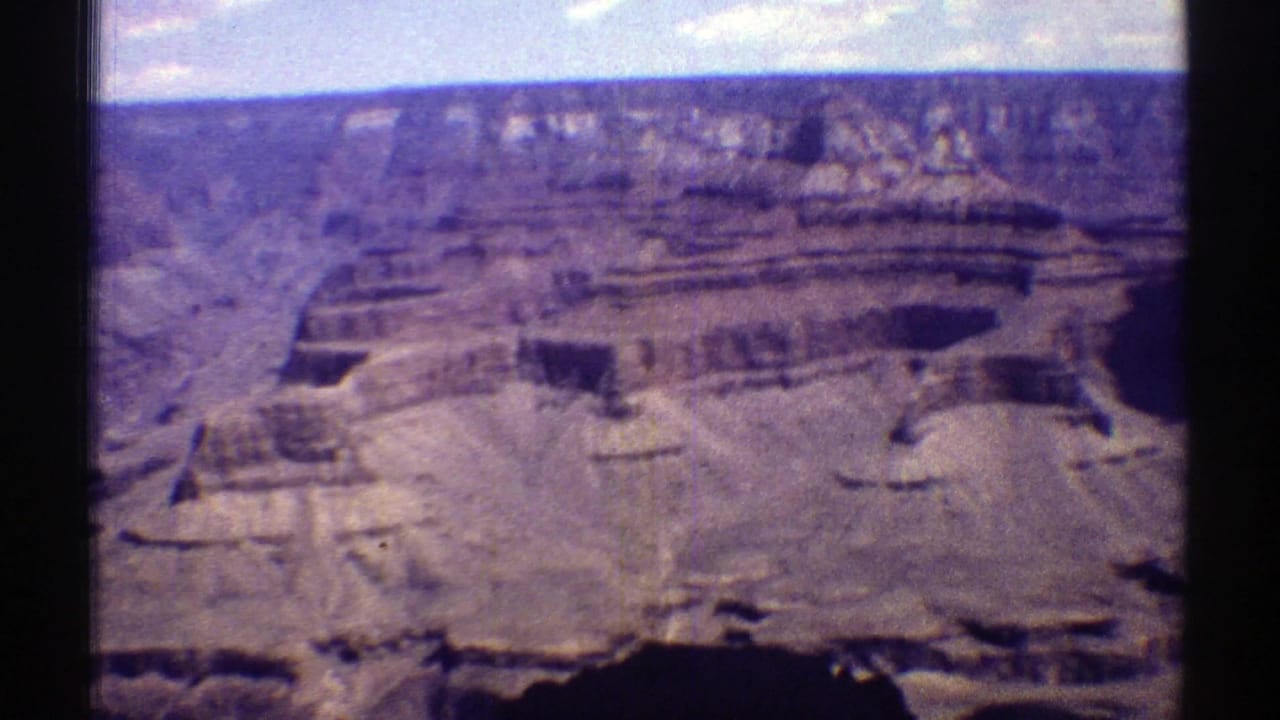 Wide 1969 Arizona canyon view from a visitor vantage point, showing layered Grand Canyon rock walls under a bright sky.